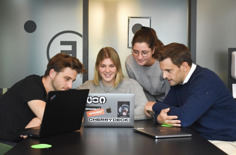 Team members gathered around the laptop to discuss relationship mapping software's key components and capabilities.